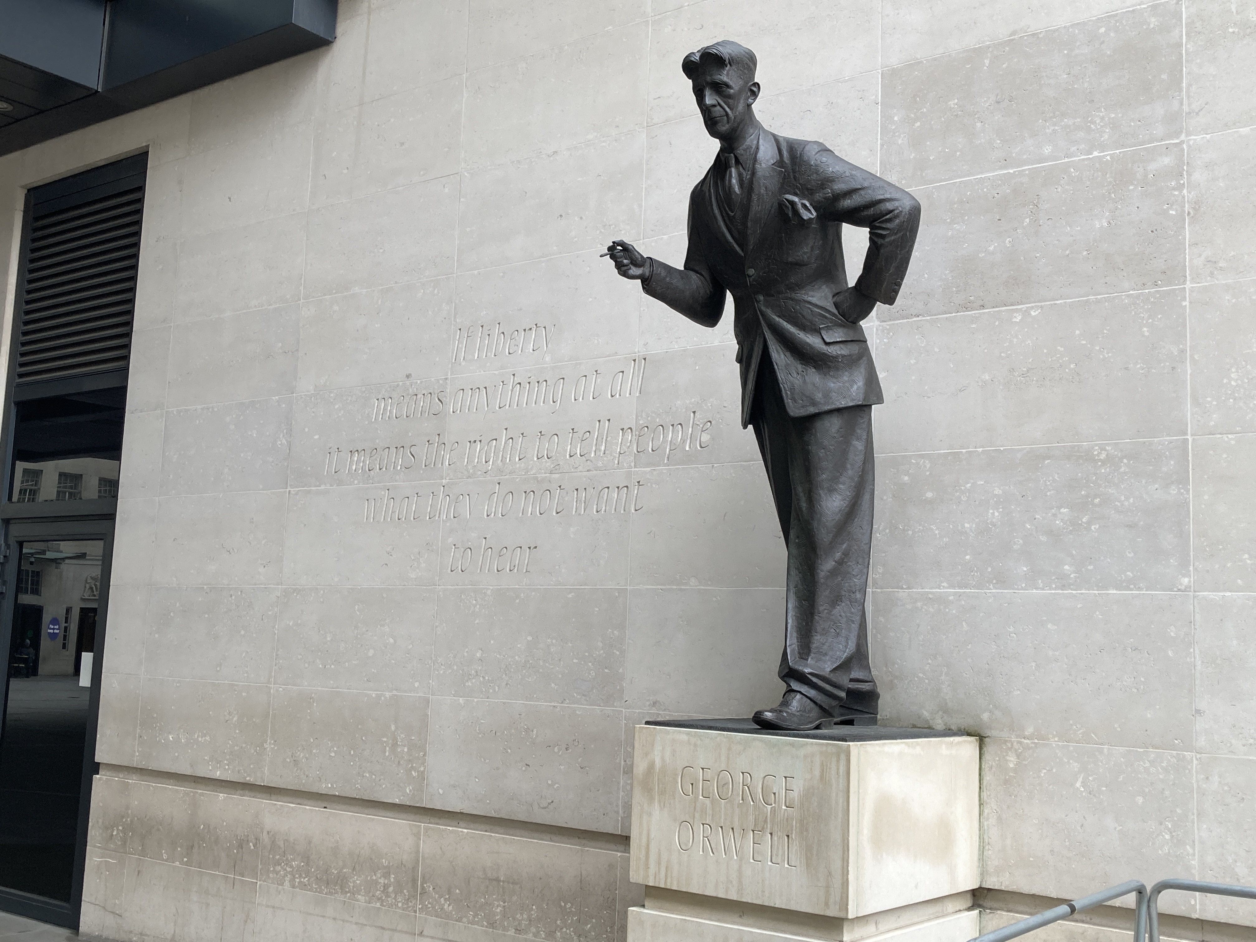 BBC New Broadcasting House 門外的 George Orwell 雕像，旁邊刻着他關於言論自由的話。雕像由 Martin Jennings 創作，於 2017 年揭幕；這張參考照片攝於 2023 年。